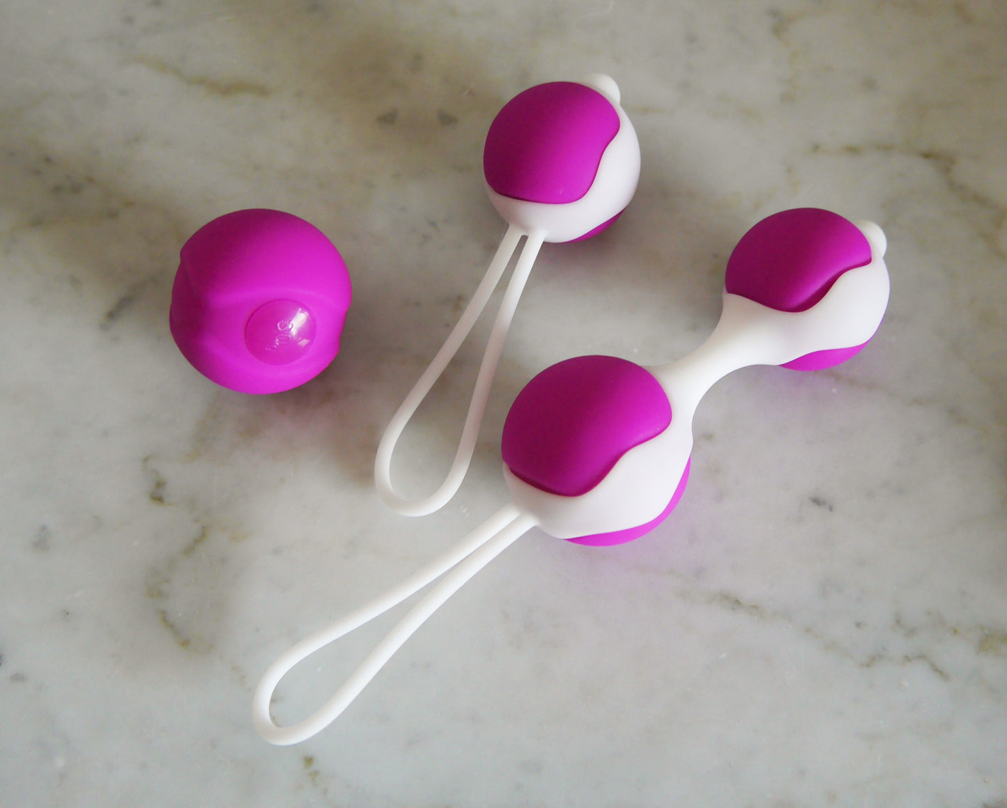 Roze-witte bekkenbodemballenset met enkele bal en dubbele bal op marmeren ondergrond