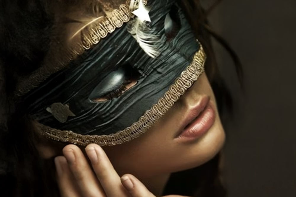 Vrouw met een elegant zwart masker met gouden details, zacht verlicht, die een mysterieuze en sensuele sfeer oproept.