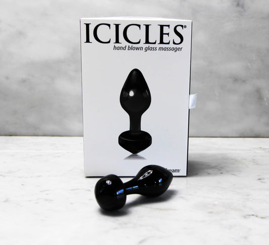 Handgeblazen glazen buttplug Icicles, zwart, met witte verpakking op marmeren ondergrond.