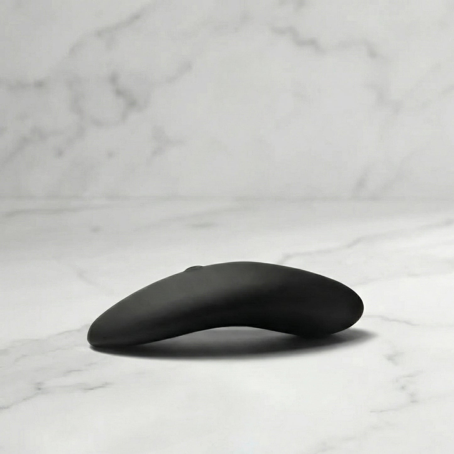 Zwarte Aludra stimulator met gebogen ergonomisch design op marmeren ondergrond