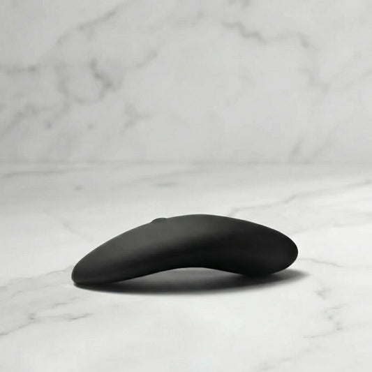 Zwarte Aludra stimulator met gebogen ergonomisch design op marmeren ondergrond