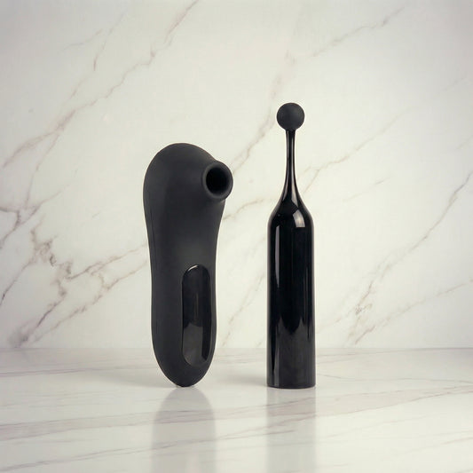 Zwarte Rocky luchtdruk-vibrator en Rock Star vibrator naast elkaar op marmeren ondergrond