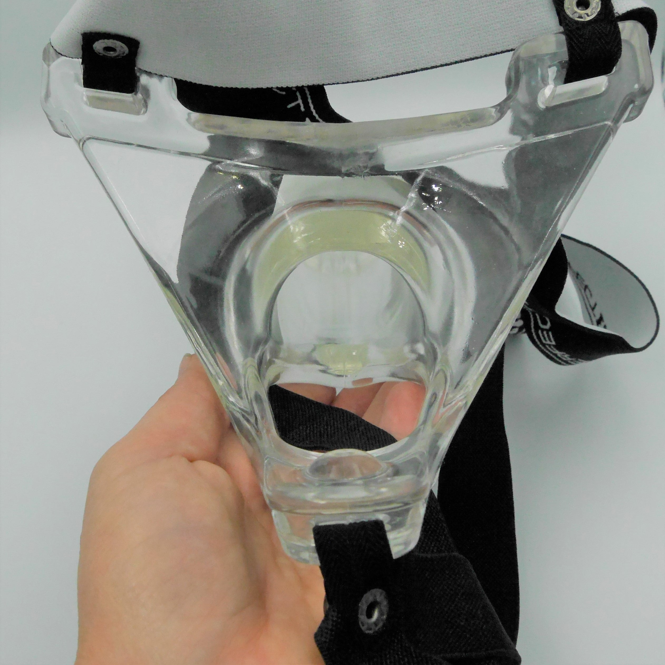 Achterzijde transparante holle prothese bevestigd aan zwart harnas, vastgehouden door hand