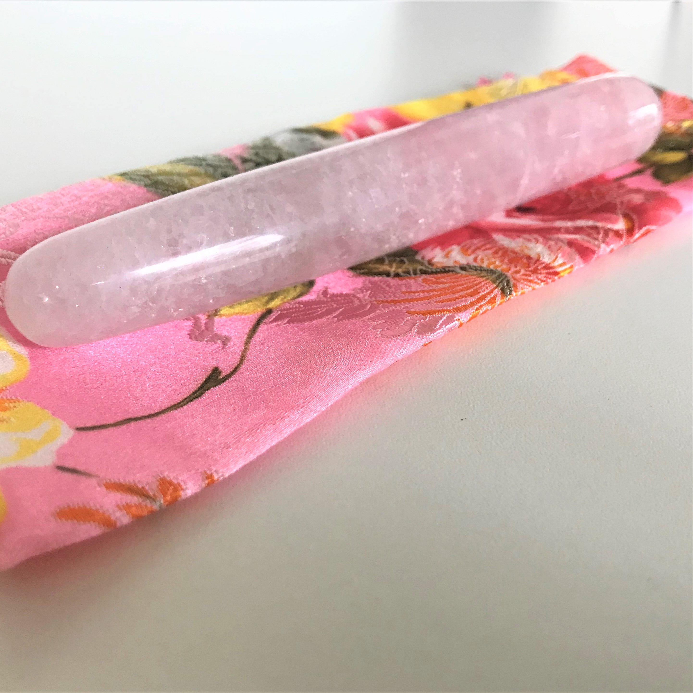 Zijaanzicht van roze natuursteen massage wands in twee verschillende groottes voor wellness rituelen