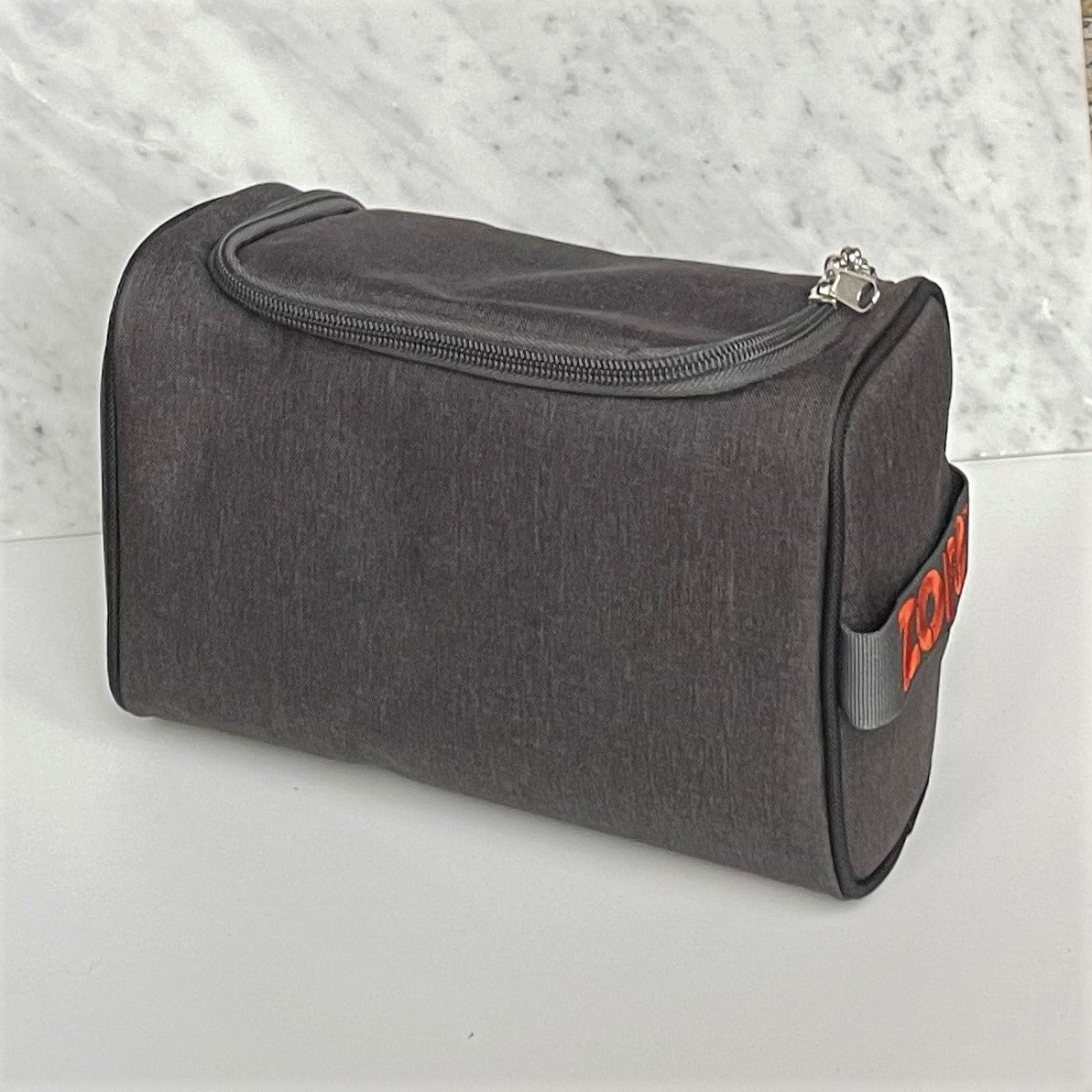Donkergrijze opbergtas met rits en oranje merklogo op marmeren achtergrond