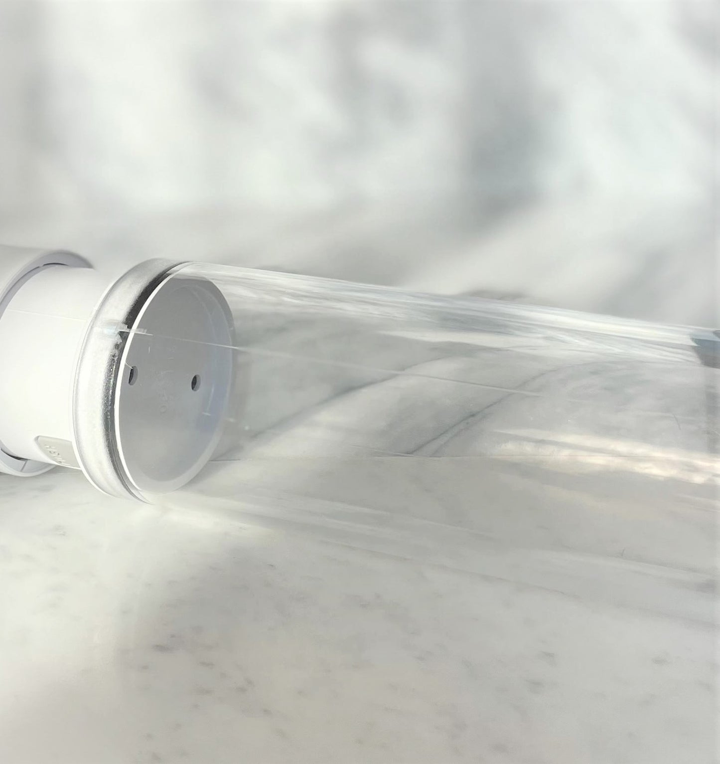 Close-up transparante cilinder van Primus penispomp met witte basis op marmeren ondergrond