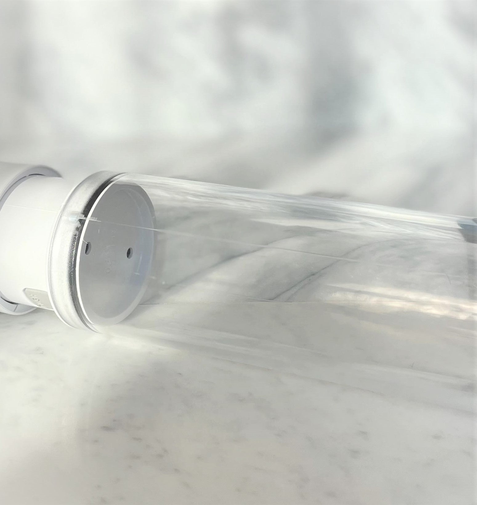 Close-up transparante cilinder van Primus penispomp met witte basis op marmeren ondergrond