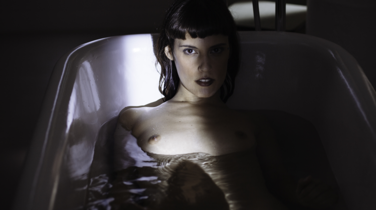 Vrouw met donker kort haar kijkt verleidelijk vanuit een bad in sfeervolle donkere belichting, XConfessions Vol. 6